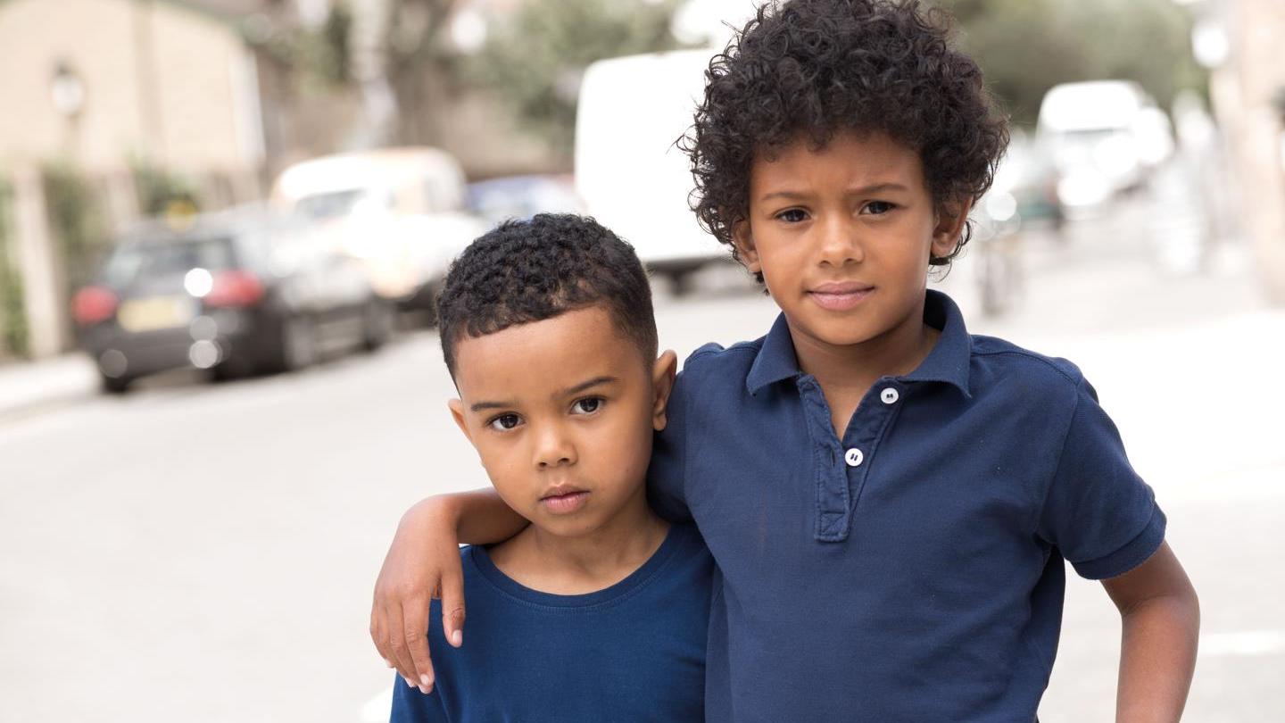 Two young boys pose in blue shirts with their arms around each other