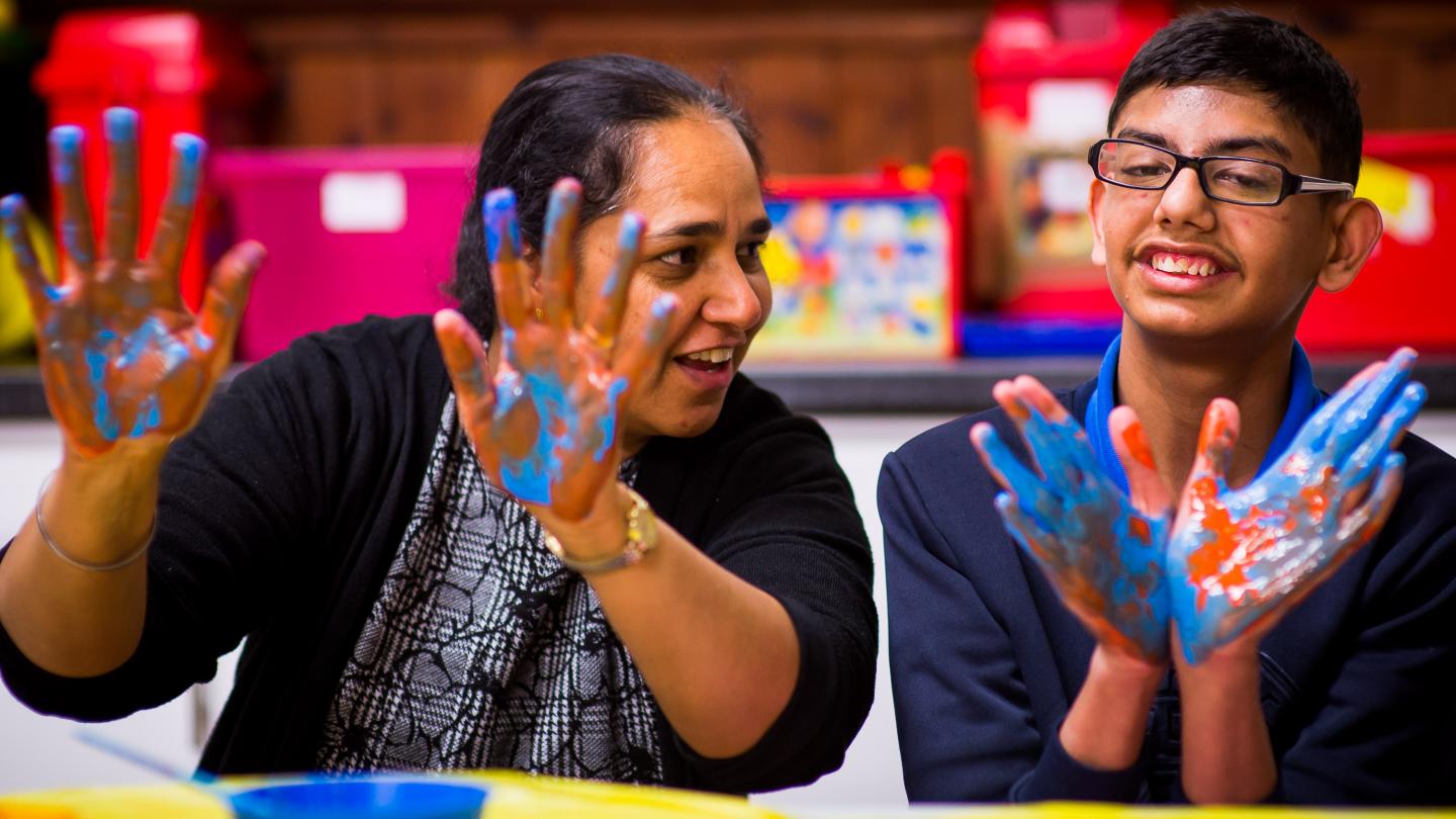 Boy and staff member using finger paints