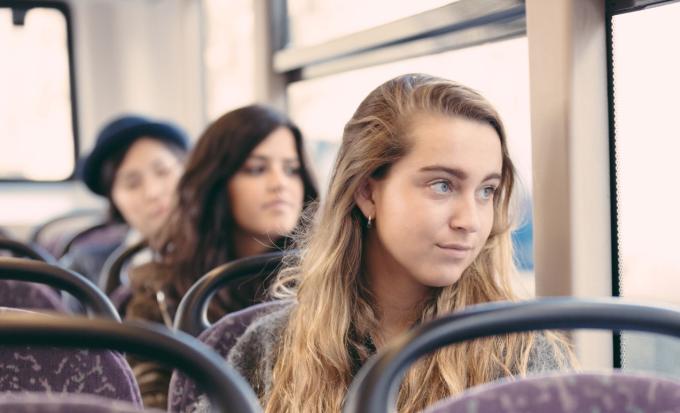 A young woman stares out of a bus window