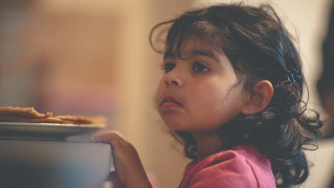 little girl standing beside a plate of food