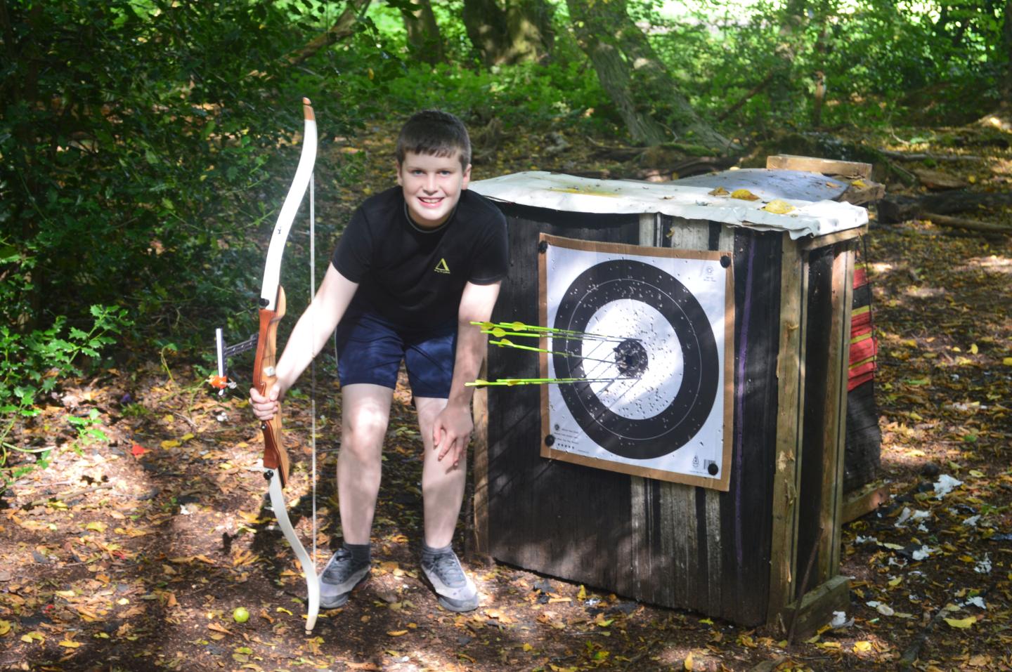 A young boy standing beside an archery board