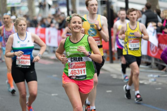 A woman in a Barnardo's running vest smiles during the London marathon