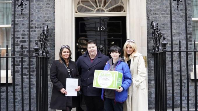 Actress Michelle Collins, Barnardo's CEO Lynn Perry and young people Jake and Dasha stand with a petition in front of the door of 10 Downing Street