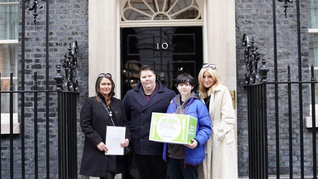Lynn Perry, Michelle Collins and young people stand with a petition in front of 10 Downing Street.