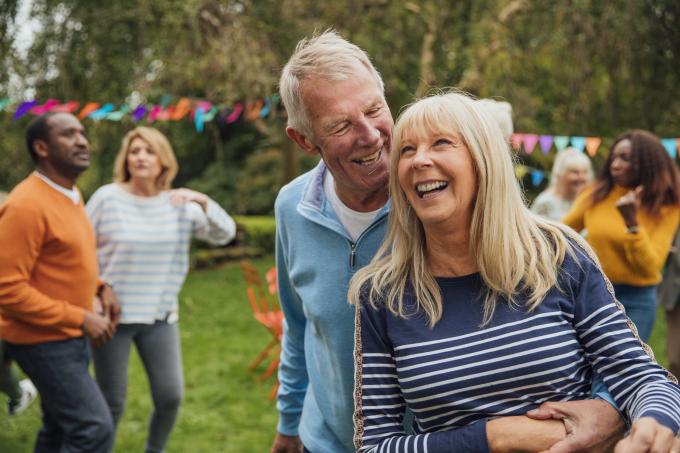 A man and wife hug and laugh at a garden party celebration