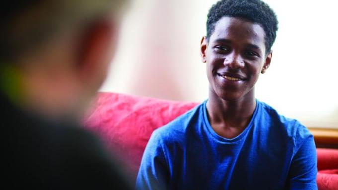 a young man in a blue shirt smiles at a Barnardo's support worker opposite him
