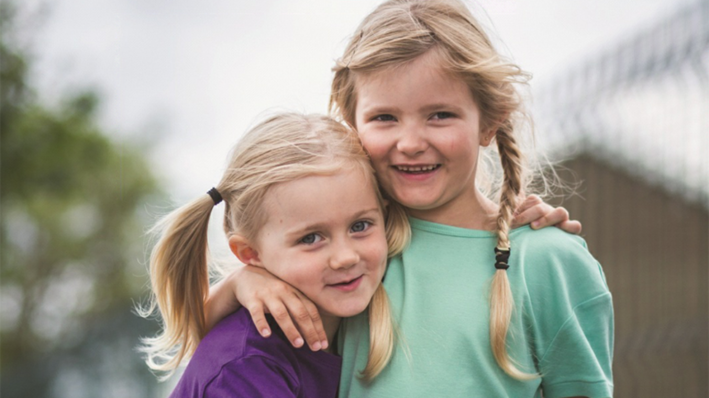 Two small girls smiling with their arms around each other